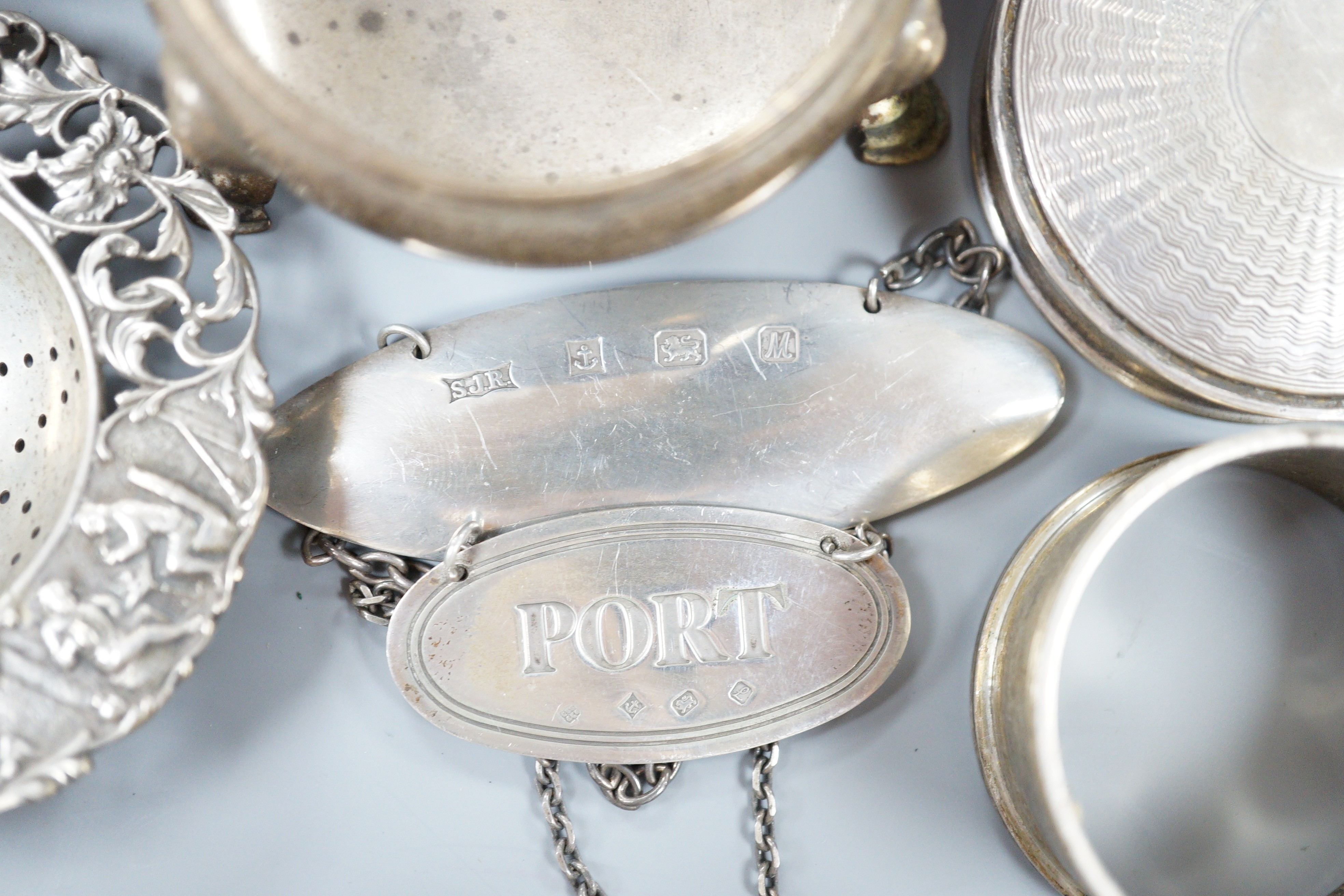 A collection of small silver items including napkin rings, repousse oval boxes, pair of bun salts, two ashtrays and a mounted table lighter, two modern wine labels, small box and three continental white metal items inclu